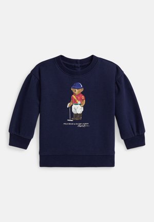 Tmavě modrá dětská mikina s dlouhým rukávem s potiskem medvídka oblečeného v polo oblečení a textem „Polo Bear by Ralph Lauren“ pod ním.