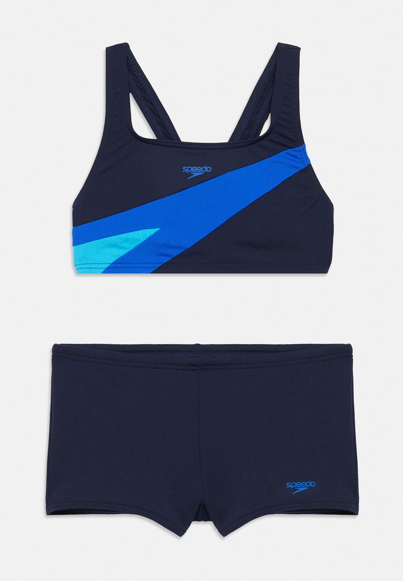 Μπλε ναυτικό μπικίνι τοπ με ανοιχτό μπλε διαγώνια ρίγα, συνδυασμένο με σορτς σε μπλε ναυτικό χρώμα. Κατασκευασμένο από ελαστικό και απαλό υλικό. Το λογότυπο της Speedo είναι ορατό.