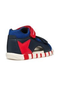 Sneaker blu navy e rossa con accento a stella, dotato di rete traspirante, fibbia regolabile e suola in gomma bianca con strisce rosse.