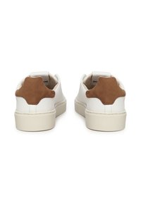 Sneakers bianchi in pelle con dettaglio in suede beige sul tallone, punta rotonda e suola piatta in gomma, dal design pulito e minimalista.