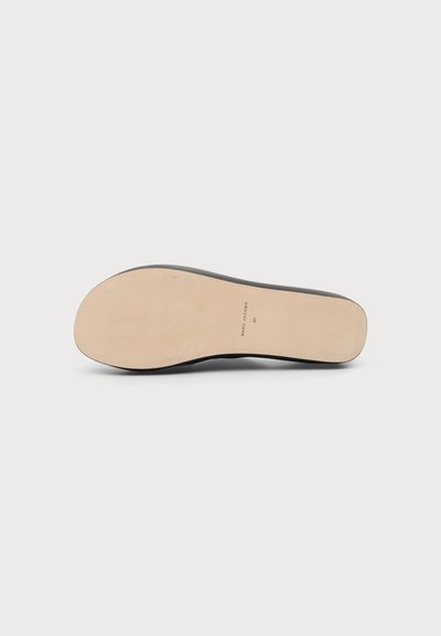Semelle d'une chaussure noire avec un dessous beige lisse, marqué de la marque "Marc Jacobs" et de la taille "40" au centre.