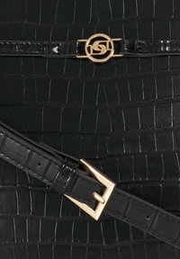 Black faux leather handbag featuring a crocodile texture, gold hardware, and a circular logo accent with a buckle strap detail.