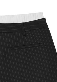 Pantalons à rayures noires avec une ceinture élastiquée blanche et une poche arrière. Le tissu a une texture lisse et un design structuré.