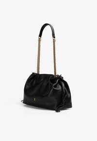 Sac à main en cuir noir avec un design froncé, doté d'une chaîne dorée et d'un petit accent en forme de skull. Texture lisse avec une apparence douce.