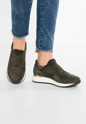 Baskets de sport vert olive en suède, dotées de bandes élastiques, d'une semelle intermédiaire blanche et d'une touche dorée au niveau du talon.