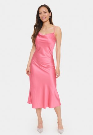 Rochie midi din satin roz, cu bretele subțiri, decolteu în V și margeană evazată. Model purtând tocuri ascuțite, de culoare deschisă, embellizate.