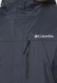 Marineblaue Jacke von Columbia mit durchgehendem Reißverschluss, strukturiertem Stoff und Kapuze. Verfügt über ein weißes Logo im Brustbereich.