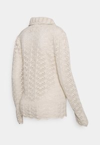 Suéter leve, de malha na cor creme, apresentando um padrão texturizado, mangas longas e gola. Detalhe de bainha ondulada na parte inferior.