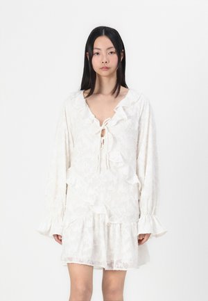 White dress with textured floral pattern, ruffled neckline and sleeves, drawstring front, and layered skirt design.