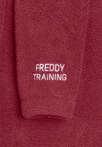 Garment in pile bordeaux con la scritta "FREDDY TRAINING" ricamata in bianco. Tessuto morbido con un design leggermente oversize, ideale per il comfort.