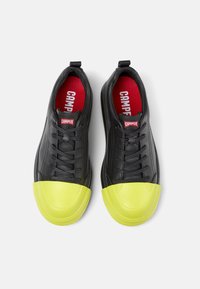 Czarne skórzane sneakersy z żółtym gumowym noskiem, czarnymi sznurowadłami oraz czerwonym wkładką z białym logo "CAMPE".