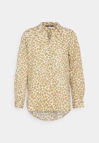 Camisa de mangas compridas em padrão de girafa castanho e branco, com colarinho abotoado e uma bainha arredondada, apresentando um ajuste descontraído.