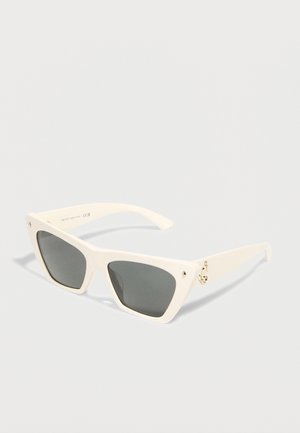 White cat-eye sunglasses with dark lenses and gold stud and logo accents on the temples, shown against a plain background.