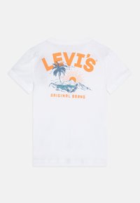 Camiseta de algodón blanca de manga corta con un gráfico colorido de palmeras, sol y montañas en la parte posterior, con el texto "LEVI'S ORIGINAL BRAND".