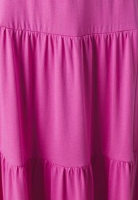 Vestido en capas rosa hecho de una tela suave. Presenta una textura fruncida a lo largo de la cintura y secciones fluidas con un acabado suave.