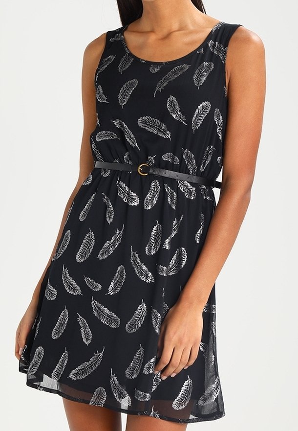Robe noire sans manches avec un motif de plumes blanches, cintrée à la taille avec une fine ceinture noire présentant une petite boucle ronde dorée.