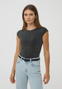 Body corto a righe nere con maniche corte e scollatura rotonda, abbinato a jeans azzurri chiari con decorazioni di perline e una cintura nera.