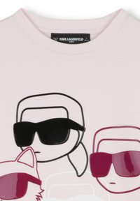 T-shirt rose clair avec des personnages de dessin animé portant des lunettes de soleil. Comprend des accents en noir brillant et en bordeaux. L'étiquette indique "KARL LAGERFELD KIDS."
