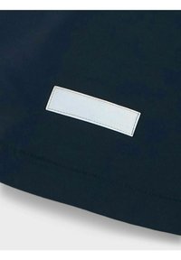 Marinfärgad tyg med en slät textur som har en vit rektangulär etikett sydd vid kanten, med diskret upphöjd text.