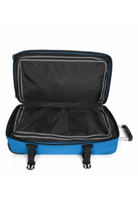 Blauer Rollkoffer mit großem schwarzem Innenraum und grauen Reißverschlüssen, ausgestattet mit einem Netzfach, Gurten und einem ausziehbaren Griff.