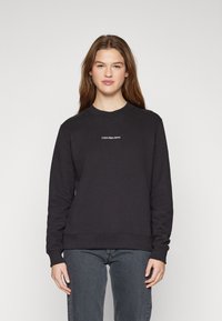 Fekete pamut keverék pulóver, kerek nyakkivágással, bordázott mandzsettákkal és hímzett "Calvin Klein Jeans" logóval a mellkasán.