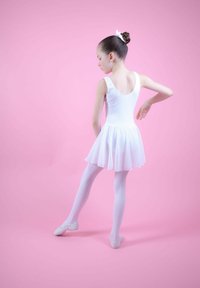 Weißes Ballettkleid mit einem ausgestellten Rock, getragen über weißen Strumpfhosen und kombiniert mit hellen Ballettschuhen. Der Hintergrund ist in einem sanften Rosaton gehalten.