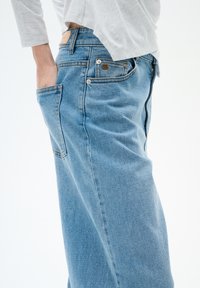 Světle modré džíny z denimu s rovný střihem, postranní kapsou a koženou nášivkou na zadním pásku s detailním šitím.