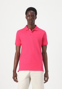 Kortærmet poloshirt i strålende pink bomuld, med klassisk krave, tre knaplukninger og lille broderet logo på brystet.