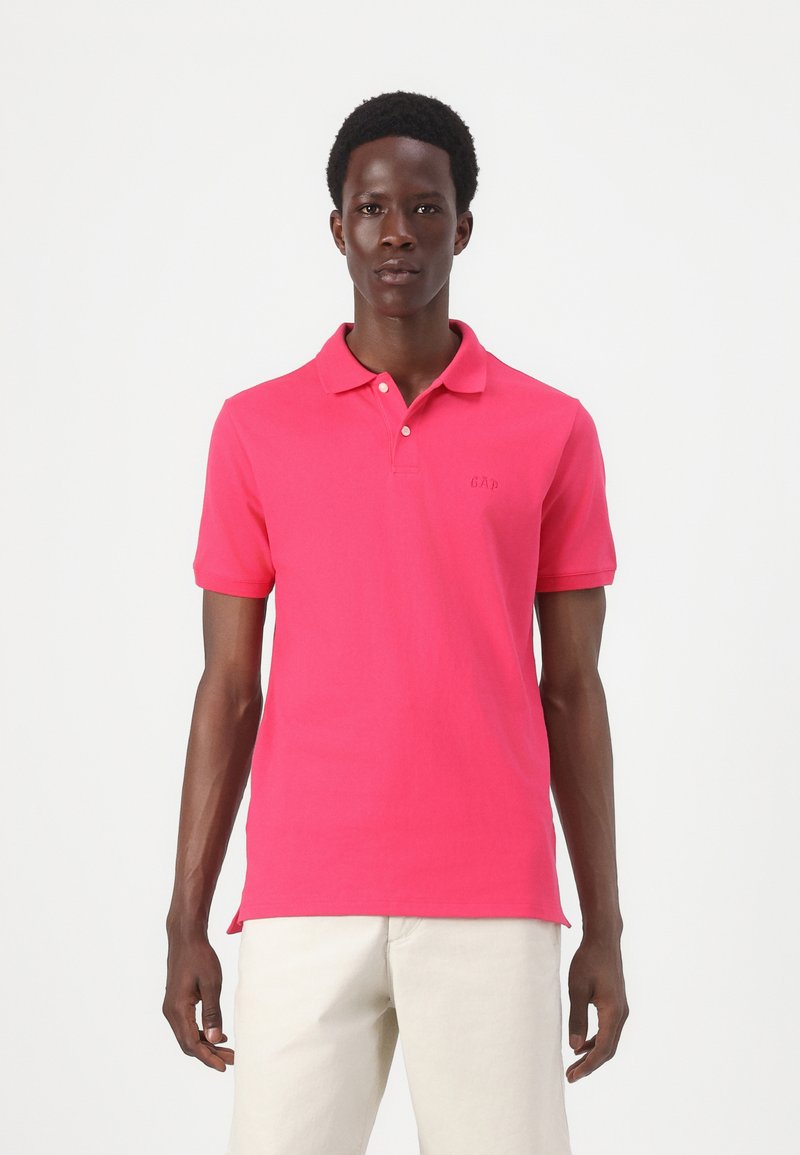 Kortærmet poloshirt i strålende pink bomuld, med klassisk krave, tre knaplukninger og lille broderet logo på brystet.