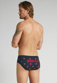 Navyblaue Schwimmshorts mit einem Spider-Man-Grafikdruck in Rot, einem figurnahen Schnitt und weichem Stoff.