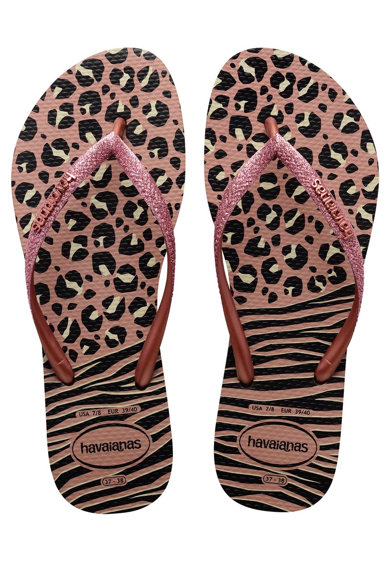 Ružové šľapky s leopardím vzorom a trblietavými strapcami v ružovo-zlatej farbe. Textúrovaná čierno-hnedá pruhovaná podošva. Názov značky "havaianas" je viditeľný.