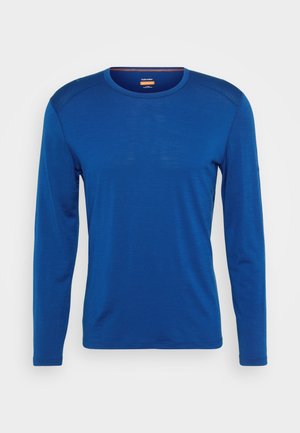 Langermet skjorte i dyp blå, laget av lettvektig stoff. Har rund hals, flate sømmer og en jevn tekstur.