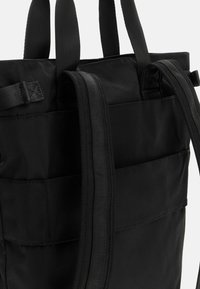 Borsa a tracolla nera realizzata in tessuto resistente, con manici piatti e robusti, una forma strutturata e dettagli di tasche esterne lungo il lato.