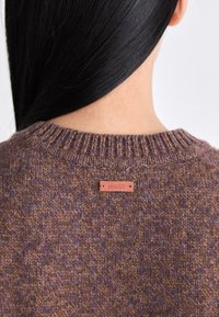 Brauner Strickpullover mit strukturiertem Muster, einem gerippten Dekolleté und einem Lederetikett, das die Marke "sessùn" auf der Rückseite zeigt.