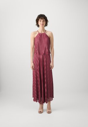 Bordeaux plissé maxi-jurk met halternek, vloeiende silhouet en semi-doorzichtig onderzoom. Gemaakt met naaktkleurige hoge hakken.