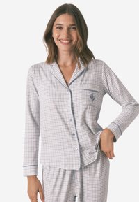 Jasnoniebieski zestaw piżamowy w biało-niebieską kratę, z długimi rękawami, kieszonką i niebieskimi wykończeniami. Wykonany z miękkiego, lekkiego materiału.