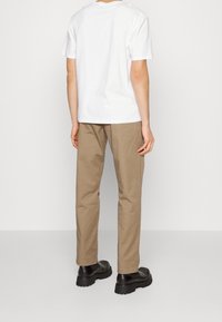 Witte katoen T-shirt met korte mouwen, gecombineerd met beige rechte chino's en zwarte schoenen met een dikke zool.