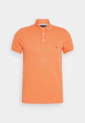 Orange polo t-shirt lavet af bomuld, med ensfarvet design, tre-knaps lukning og et lille logo på venstre bryst. Korte ærmer.