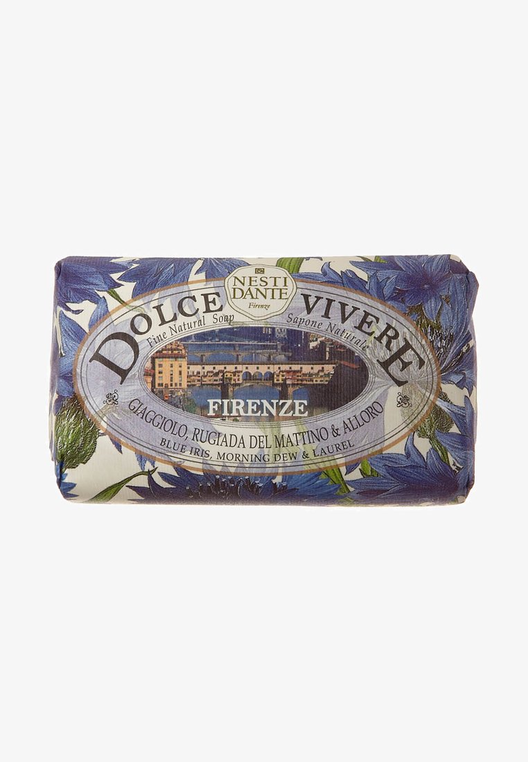 Nest Dante Firenze soap bar features a floral design with blue irises, wrapped in paper with a landscape and gold accents.