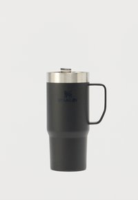 Stainless steel travel mug with a matte black finish, cylindrical shape, curved base, sturdy handle, and a silver lid with a spout.