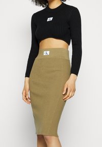 Svart ribbad kort topp med rund halsringning, parat med en khaki ribbad midiklänning. Båda har märkta logotags.