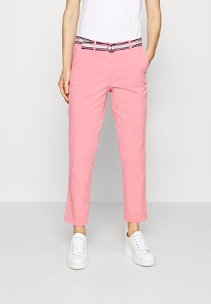 Rosa bomull byxor med en kortad design och ett randigt bälte. Matchande vita sneakers fulländar outfiten.