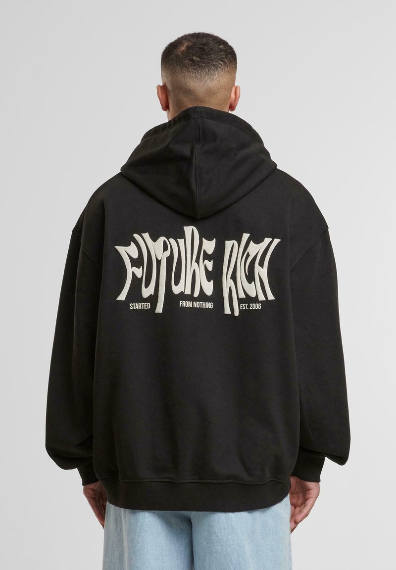 Sudadera negra con un corte holgado, que presenta un gran texto blanco en la parte posterior que dice "FUTURE RICH" y detalles adicionales abajo.