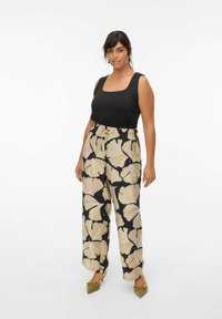 Black square-neck tank top paired with beige floral-patterned wide-leg pants featuring a drawstring waist. Model wearing green pointed flats.