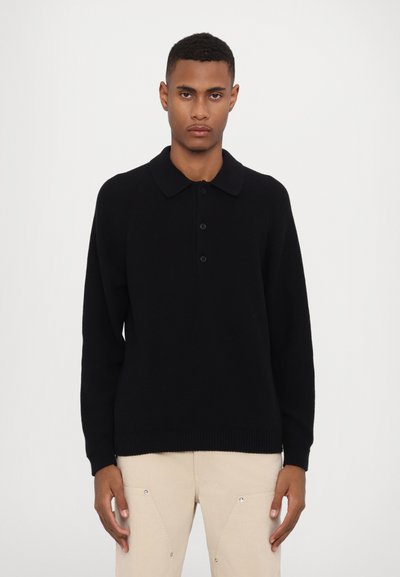 Suéter de polo de punto negro con cuello tipo polo, tres botones y dobladillo acanalado. Mangas largas con una textura suave.