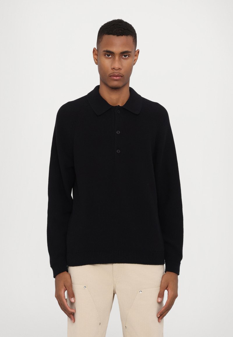 Pull polo tricoté noir avec un col, trois boutons et un ourlet côtelé. Manches longues avec une texture lisse.