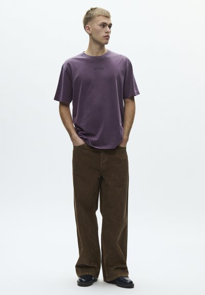 Lilla bomulls t-skjorte med rund hals og avslappet passform, kombinert med brune vide bukser med teksturert finish.
