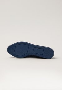 Blue rubber shoe sole with textured grip patterns, rounded toe, and flat heel. Features a smooth finish with one rectangular accent.