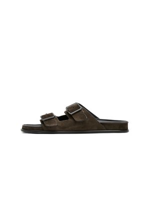 Sandale mule en daim brun foncé avec deux brides réglables à boucle et semelle plate noire, vue de profil sur fond blanc.