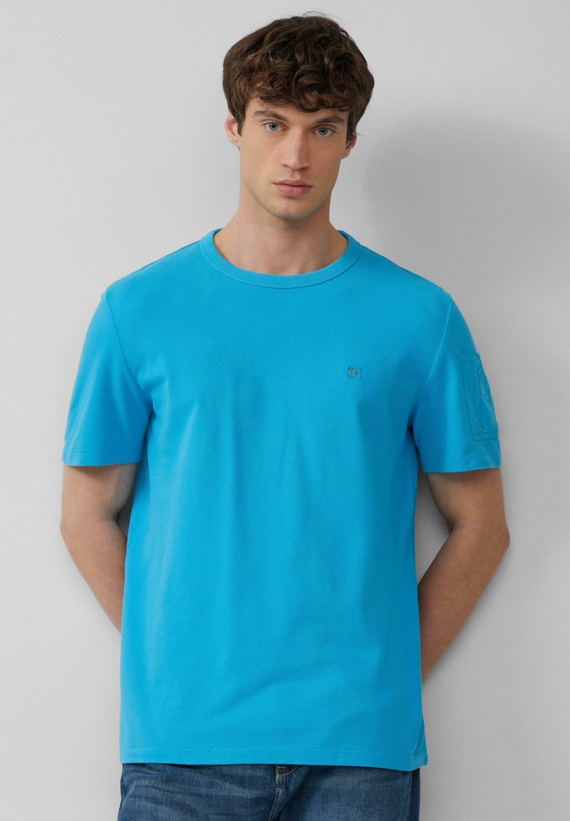 Felle blauwe katoenen T-shirt met ronde hals en korte mouwen. Bevat een klein logo op de borst en een textuurdetail op de schouders.